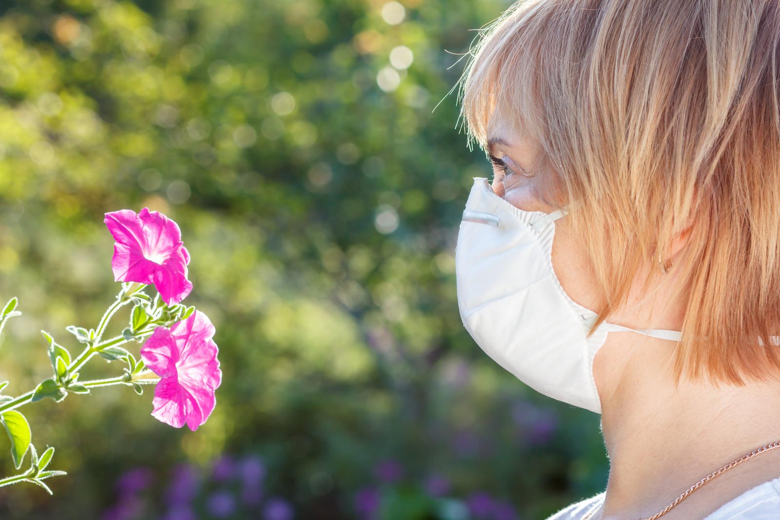 Portrait of a woman with a mask while checking the flowers.